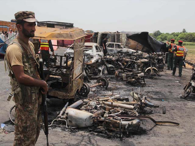 pakistani soldiers stand guard beside burnt out vehicles at the scene where an oil tanker caught fire following an accident on a highway near the town of ahmedpur east some 670 kms 416 miles from islamabad on june 25 2017 at least 123 people were killed and scores injured in an inferno that erupted after an oil tanker overturned in central pakistan early on june 25 and crowds rushed to collect fuel an official said photo afp ss mirza