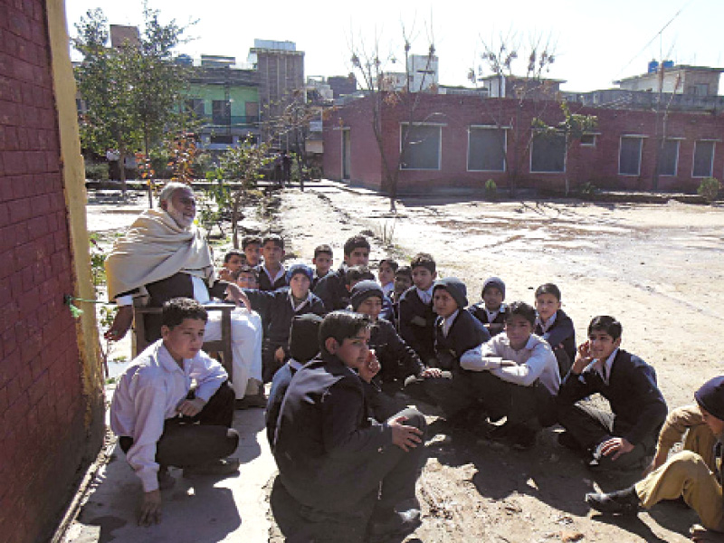 prof nisar teaches ethics to students at government boys high school khayaban e sir syed due to land disputes the students are forced to study outside the building the school playground is now being used by goats and sheep photo azam khan express