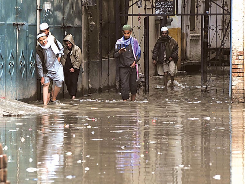 children tread through stagnant rainwater in mohallah jataan yakatoot photo muhammad iqbal express