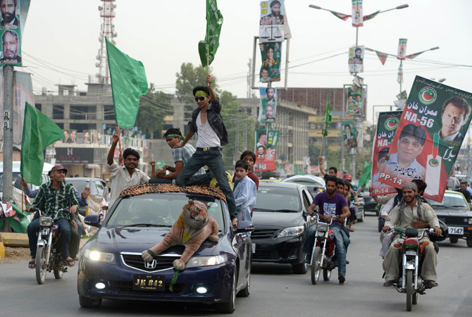 activists of pakistan tehreek e insaf pti and pakistan muslim league nawaz pml n parties carry posters and flags as they drive during the general election in rawalpindi photo getty