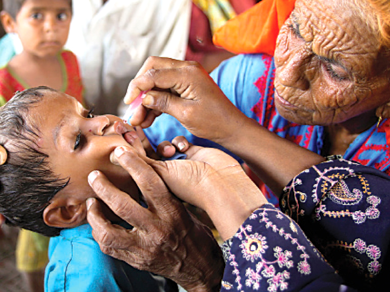 a woman administers polio vaccine to a child in bannu photo file