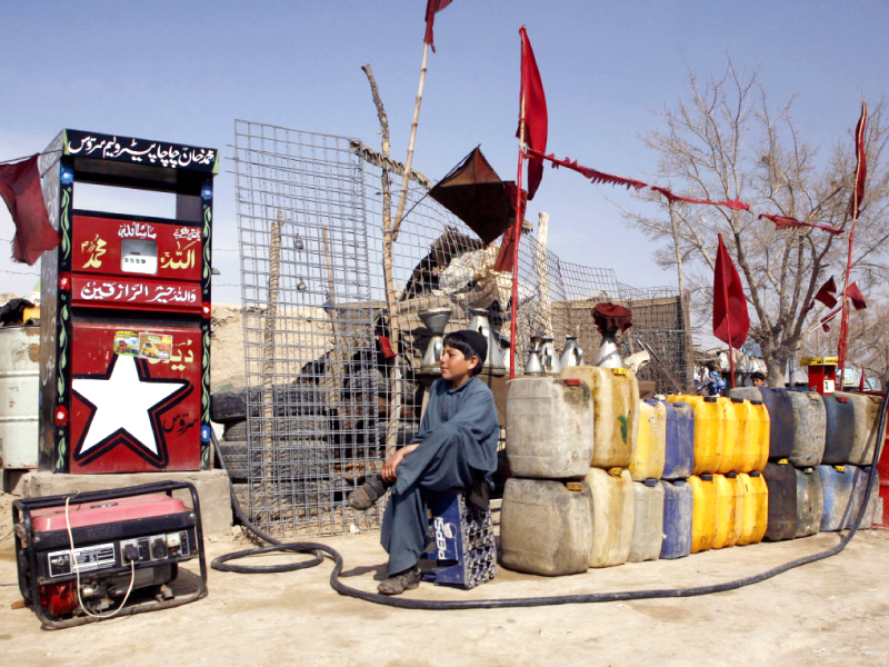 a boy sits next to plastic canisters filled with petrol that he says was brought from iran photo reuters
