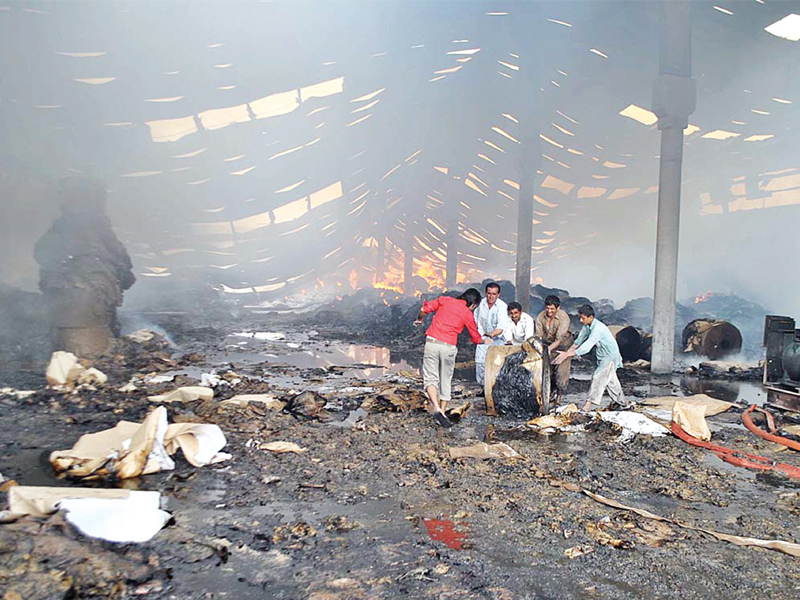 workers rummage through the burned factory in multan to see what could be reused photo app