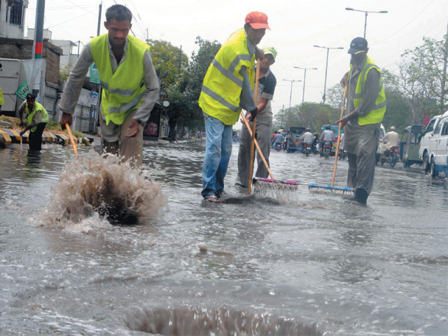 after the rain on monday morning karachi metropolitan corporation workers clear the main road in guru mandir photo express after the rain on monday morning karachi metropolitan corporation workers clear the main road in guru mandir photo express
