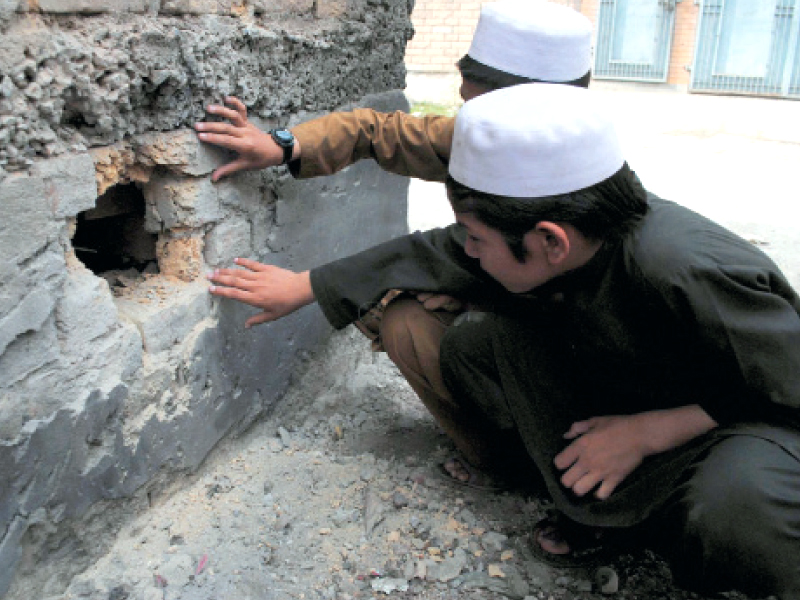 two young boys inspect a damaged wall in the wake of the attack a total of seven mortar shells were fired at the hayatabad area photo online