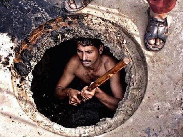 sanitary worker taking garbage out of the gutter with no safety equipment photo worldwatchmonitor