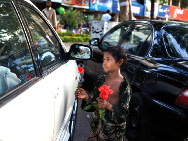 a child beggar makes a feeble attempt to earn some money by selling roses at a market in islamabad photo myra iqbal express