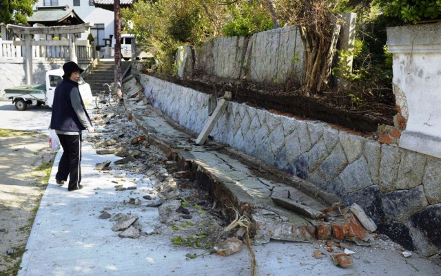 a woman walks past collapsed stone wall at a shrine after an earthquake in western japan on april 13 2013 photo reuters