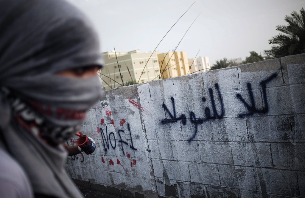 a bahraini masked protestor writes graffiti against the upcoming bahrain formula one grand prix on april 17 2013 photo afp