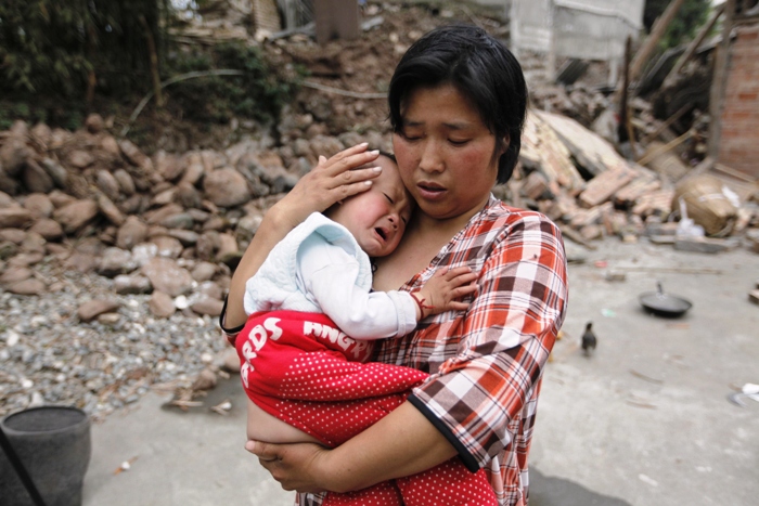 survivor chen zhirong comforts her 18 month old son next to debris at a village on the second day after an earthquake hit longmen township of lushan county sichuan province april 21 2013 photo reuters