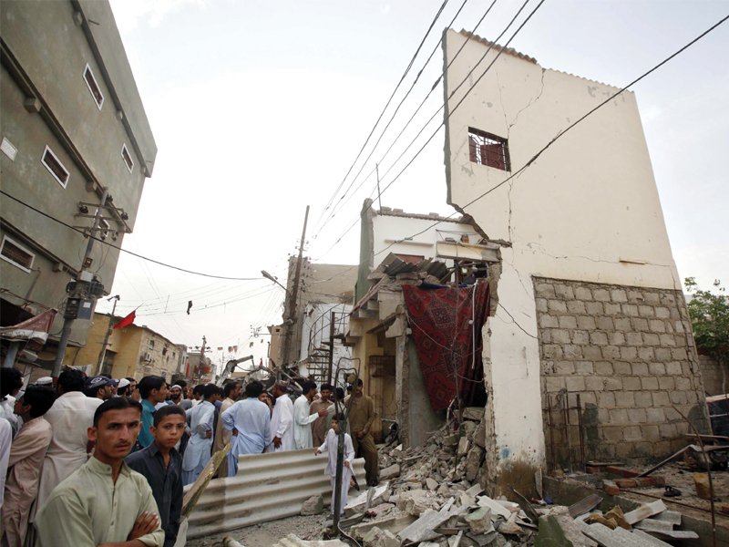 people gather outside a house in mominabad which was destroyed when a bomb went off last friday near anp s corner meeting