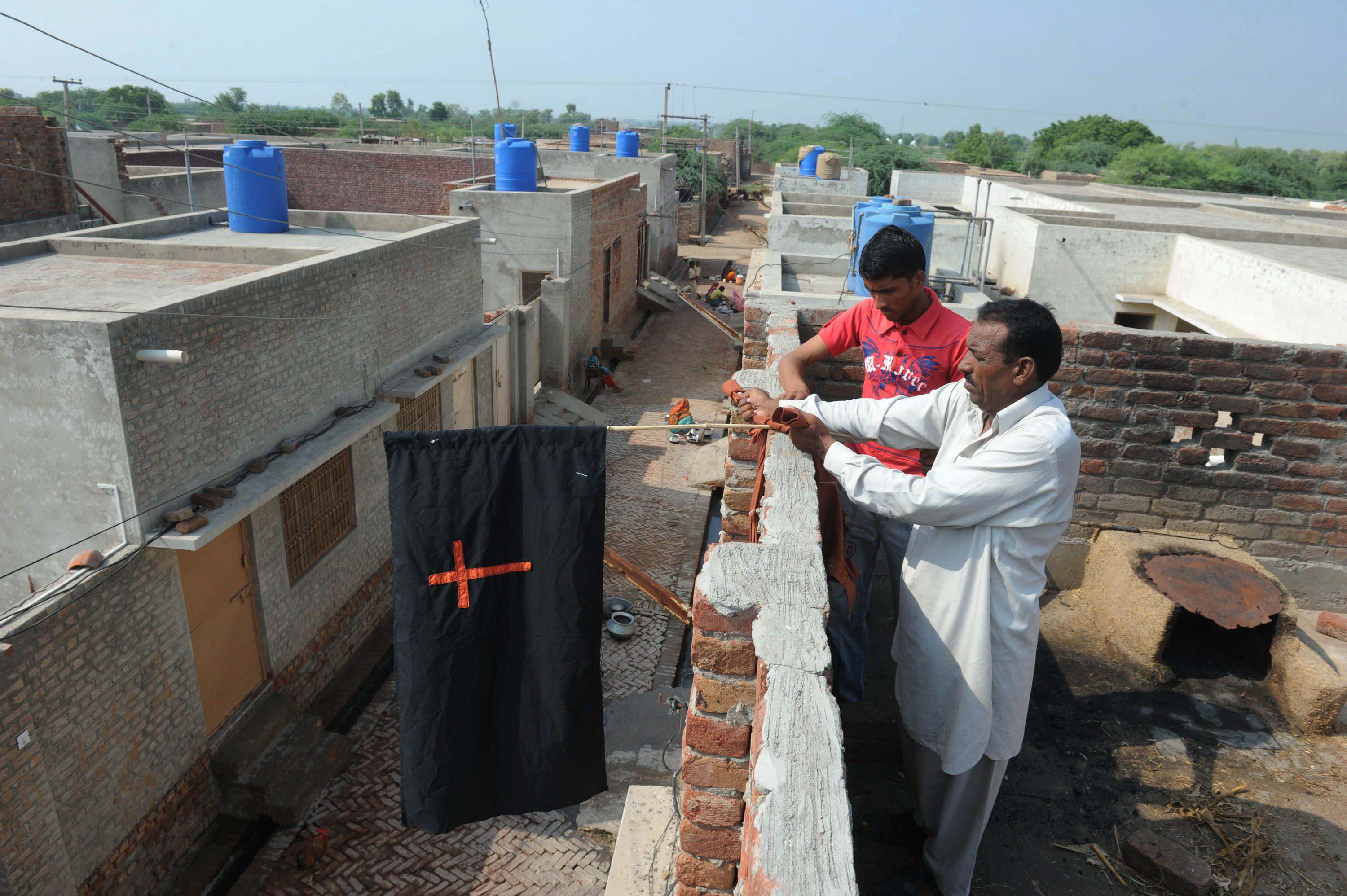 a pakistani christian resident hangs a flag with the cross symbol at his home in korian on august 30 2012 photo afp file