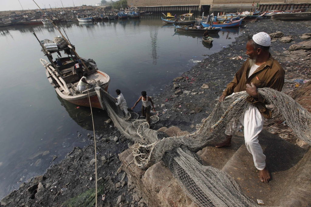 men load fish nets onto a boat before they depart for a catch at the ibrahim hyderi fish harbor some 17 km 11 miles from karachi december 7 2012 photo reuters