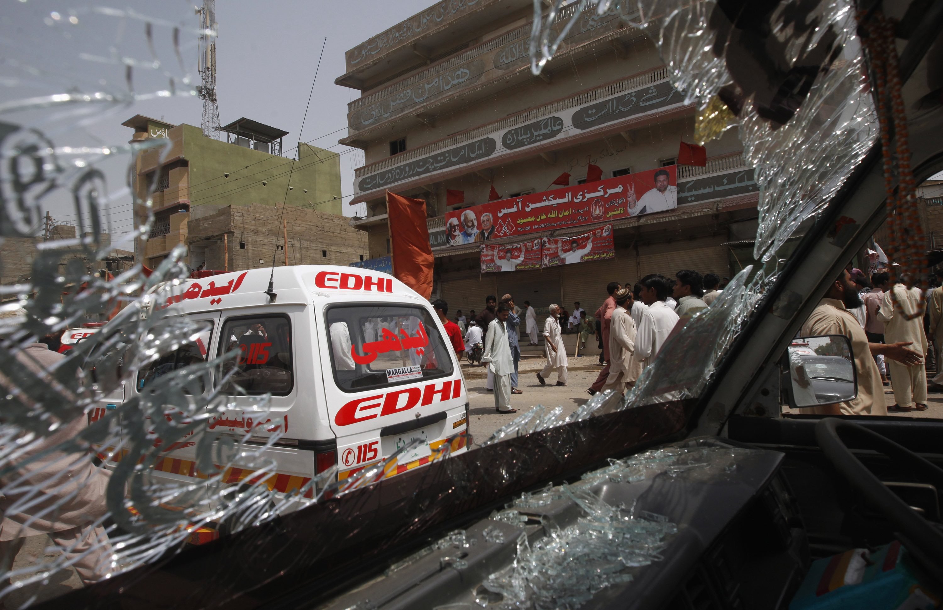 security officials and residents are seen through the shattered windscreen of a damaged vehicle at the site of a bomb attack in karachi photo reuters