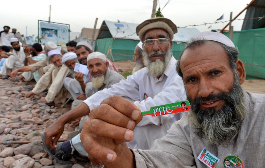 a pti supporter sits in a queue waiting for his turn to cast vote outside a polling station in jalozai camp photo afp