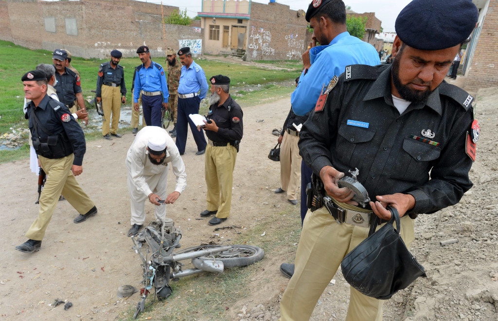 police officials examine a destroyed motorbike after a bomb explosion in peshawar on may 11 2013 photo afp