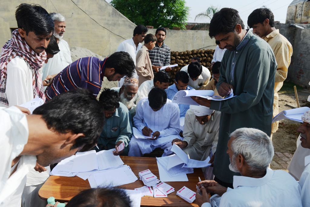 residents wanting to vote check voter registration lists near a polling station in the village of dial on the outskirts of lahore on may 11 2013 photo afp