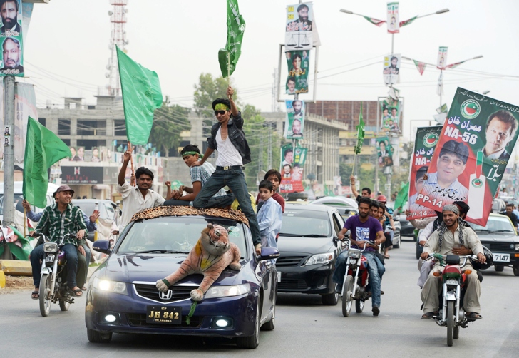 activists of pakistan tehreek e insaf pti and pakistan muslim league nawaz pml n parties carry posters and flags as they drive during the general election photo afp