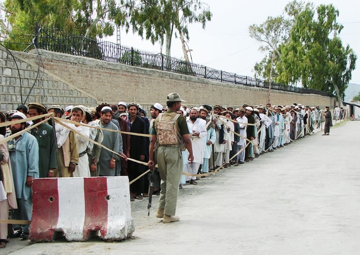 pakistani tribal voters stand in a queue as they wait for their turn to cast their votes outside a polling station in restive miranshah the main town of north waziristan photo afp