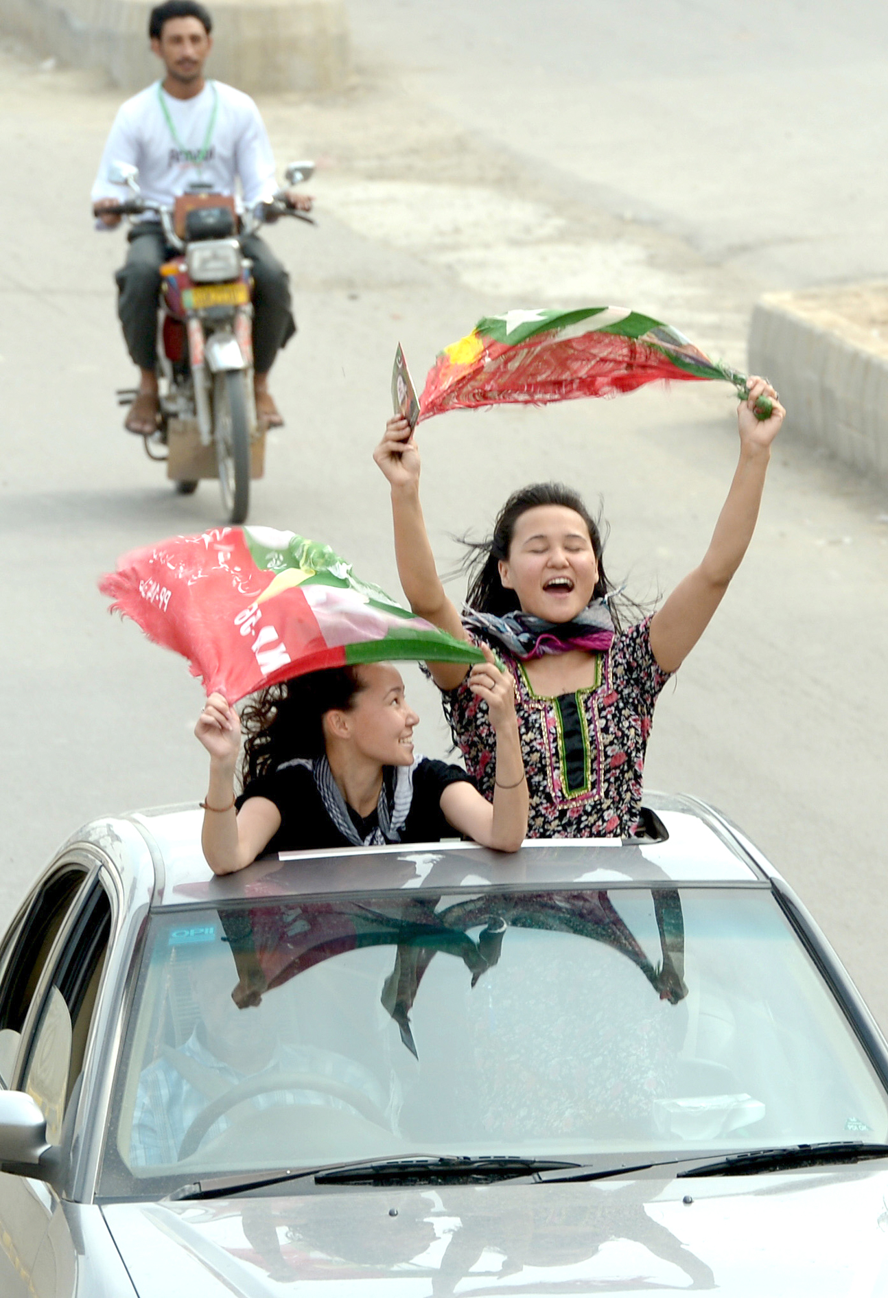 activists of pakistan tehreek e insaf pti wave party flags as they drive through the streets during the general election in rawalpindi on may 11 2013 photo afp