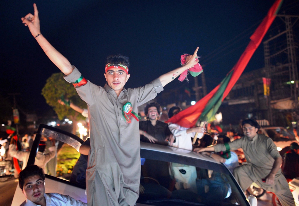 supporters of pakistani politician and former cricketer imran khan wave flags as they take part in a rally in peshawar on may 11 2013 photo afp