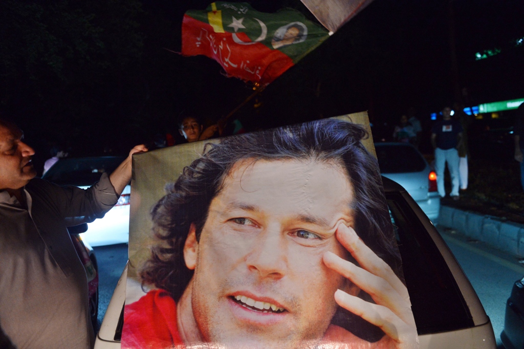 a pti supporter carries imran khan 039 s portrait as they take part in a rally in islamabad on may 11 2013 photo afp