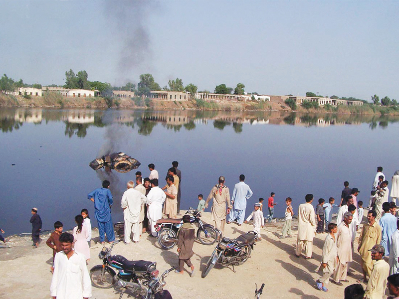 people gather to look at a truck which was torched and dumped in a pond during a protest by ppp workers in hyderabad the activists were condemning the alleged rigging on na 219 and ps 49 photo online