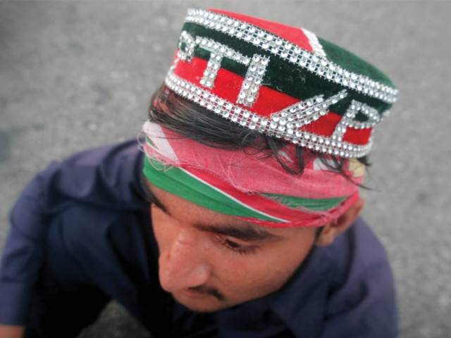 a pti supporter looks on as hundreds of people throng the rally on main university road next to expo centre on wednesday to protest against rigging in the elections photo athar khan express