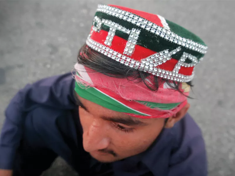 a pti supporter looks on as hundreds of people throng the rally on main university road next to expo centre on wednesday to protest against rigging in the elections photo athar khan express