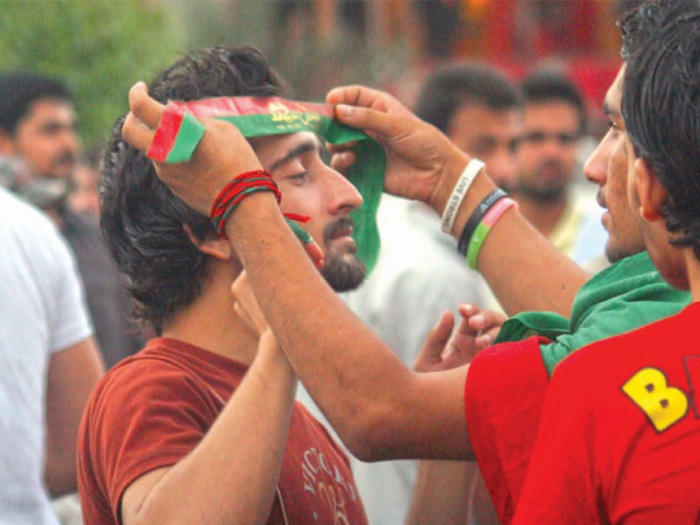 a pakistan tehreek e insaf pti supporter wraps a flag around the forehead of another protester who had turned up at the party s protest on rashid minhas road photo athar khan express a pakistan tehreek e insaf pti supporter wraps a flag around the forehead of another protester who had turned up at the party s protest on rashid minhas road photo athar khan express
