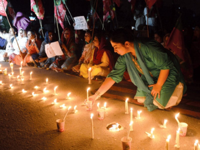 a woman lights a candle for slain pti leader zahra shahid hussain during the vigil photo afp a woman lights a candle for slain pti leader zahra shahid hussain during the vigil photo afp