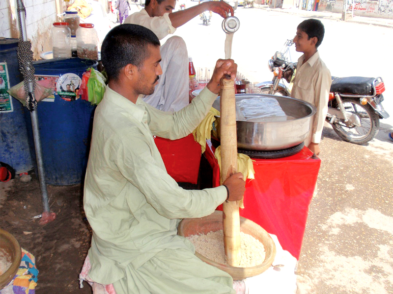 a man grinds the ingredients to make thadal a popular summer drink in sukkur photo express