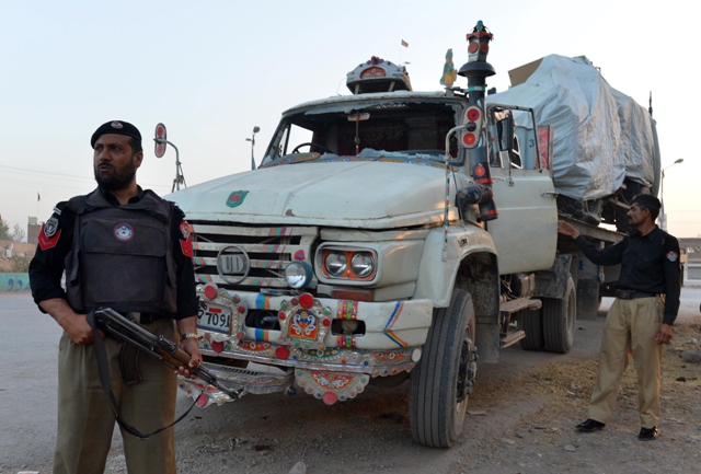 policemen stand guard beside a truck carrying a nato forces vehicle after an attack by gunmen on the outskirts of peshawar on may 16 2013 photo afp file