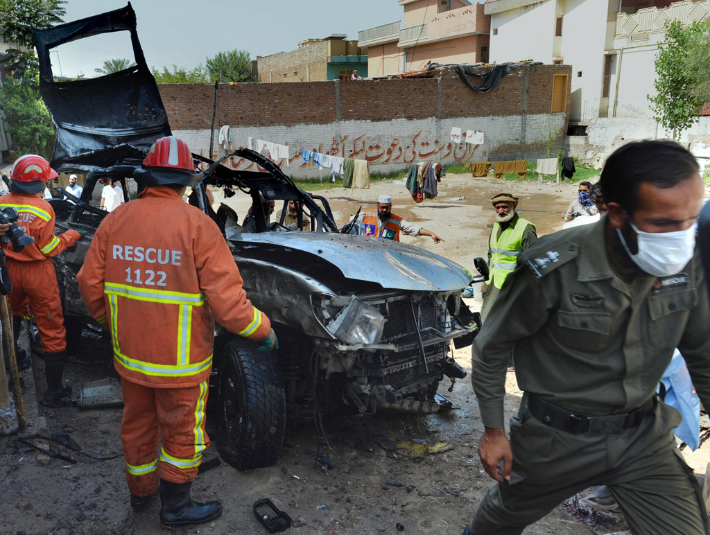 volunteers search a badly damaged vehicle after a suicide bomb attack in peshawar on may 24 2013 photo afp