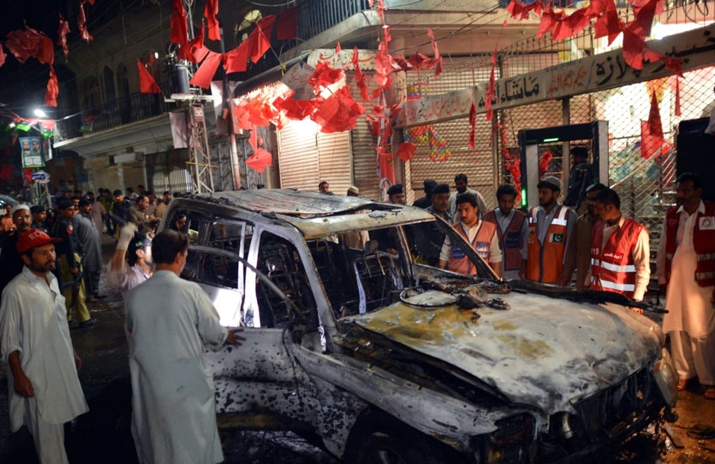 local residents and volunteers gather around a destroyed vehicle at the site of a suicide bomb attack at an election campaign rally in peshawar on april 16 2013 photo afp