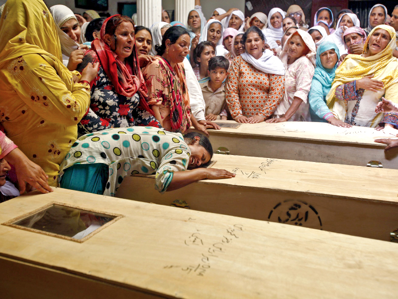 a female relative of one of the schoolchildren cries over their coffin l men stand around the burnt out school van photo reuters