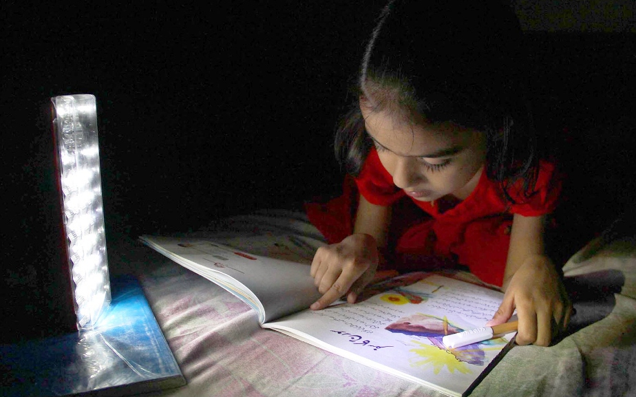 a student studying with the help of emergency light during power outage in karachi photo inp