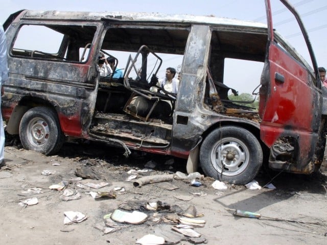 men stand around a burnt out school bus after a gas cylinder on it exploded killing seventeen children on the outskirts of gujrat photo reuters