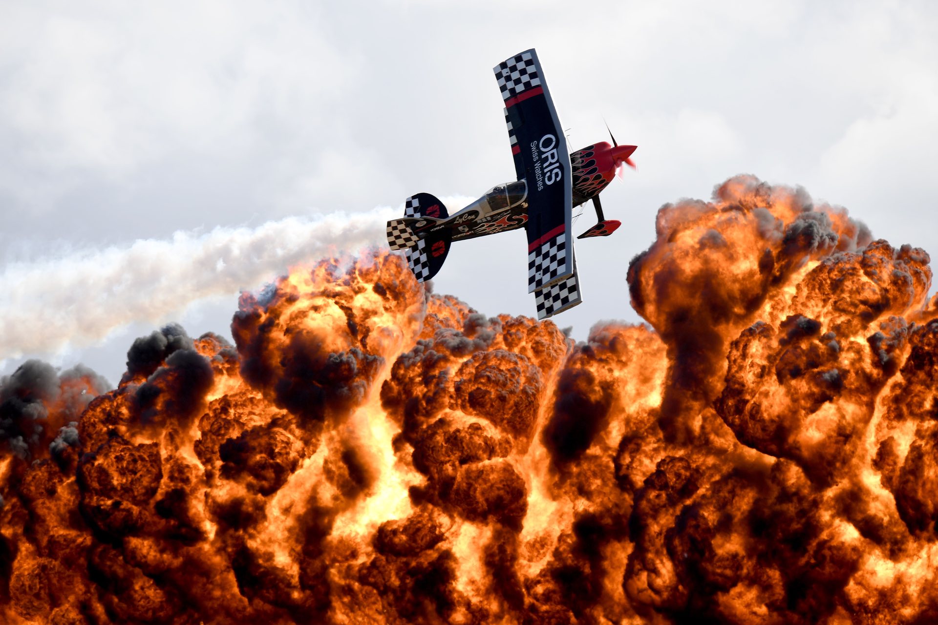 a member of the tinstix of dynamite aerobatics team flies in front of a wall of fire during the australian international airshow melbourne australia photo afp