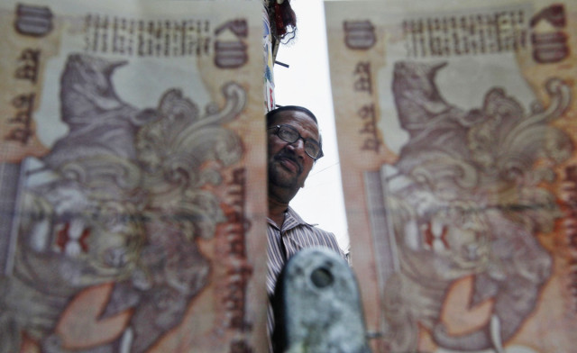 a roadside currency exchange vendor is pictured through indian rupee notes in the old quarters of delhi may 31 2013 photo reuters