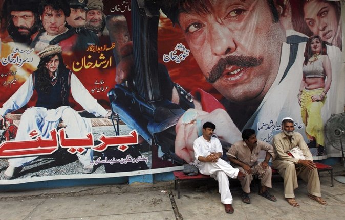 cinema workers sit near a poster of a pashto movie at arshad cinema in peshawar may 27 2013 photo reuters