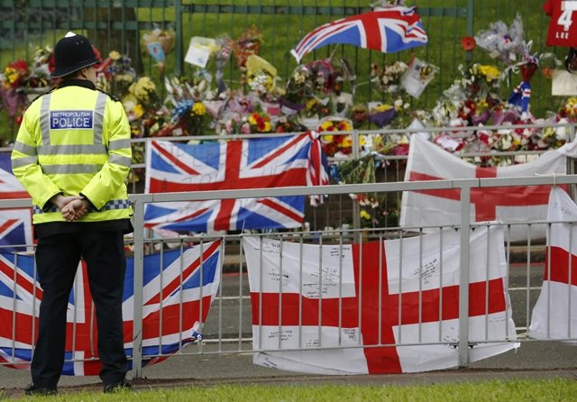 a police officer stands next to floral tributes flags and balloons left for british soldier lee rigby near the scene where he was killed in woolwich southeast london may 28 2013 photo reuters