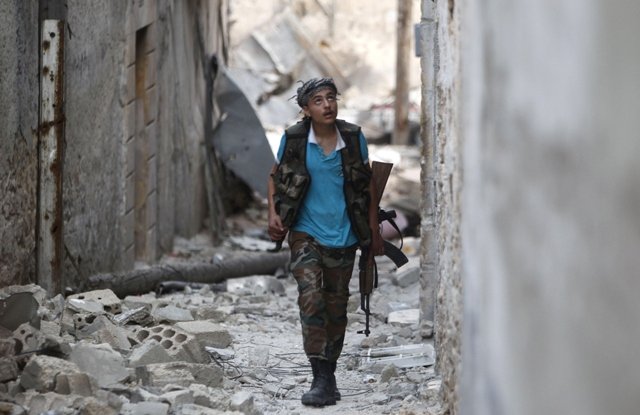 a member of the free syrian army walks with his weapon in a damaged street filled with debris in aleppo 039 s karm al jabal district june 3 2013 photo reuters