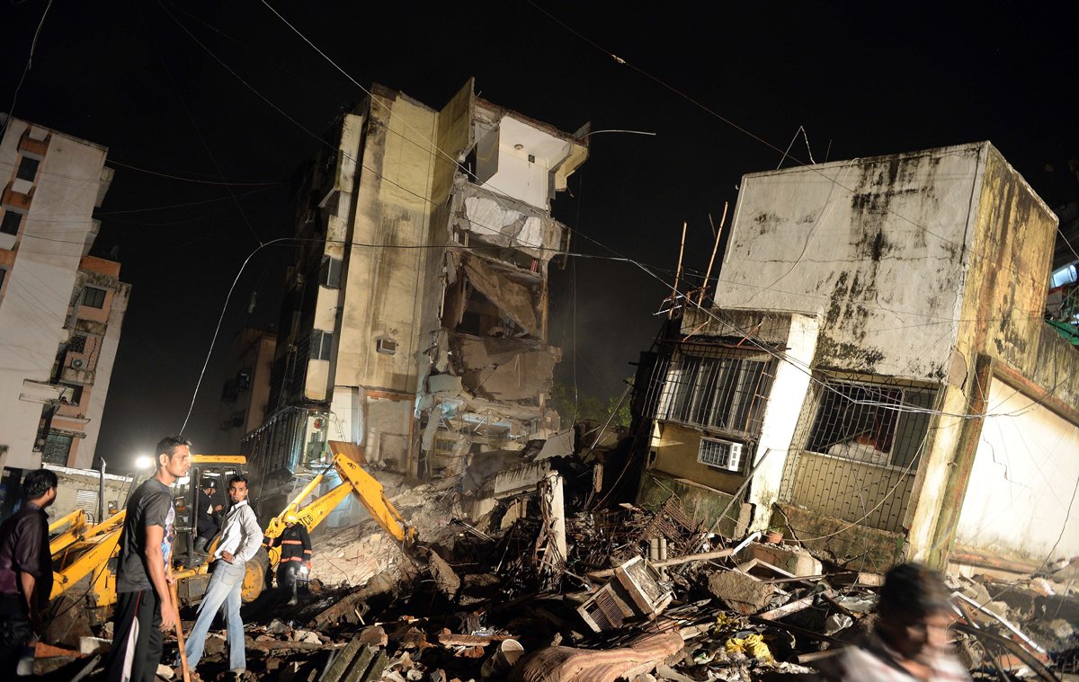 an excavator clears debris as local residents look for trapped people after a residential building collapsed in mumbai photo afp