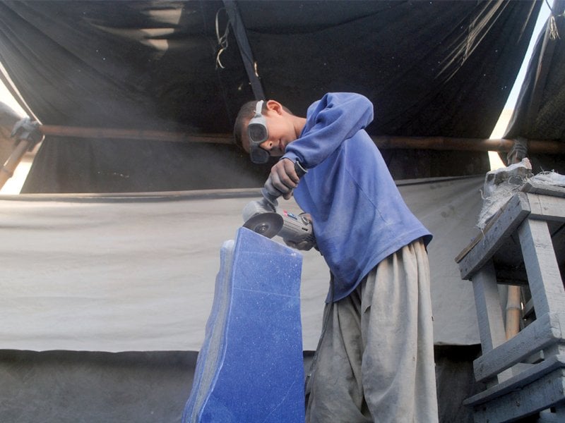 twelve year old asadullah a fifth grader is busy cutting a gemstone at namak mandi photo muhammad iqbal express