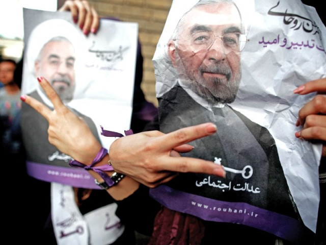 iranian women flash the sign for victory as they hold portraits of hassan rowhani during celebrations after he won the islamic republic s presidential elections photo afp