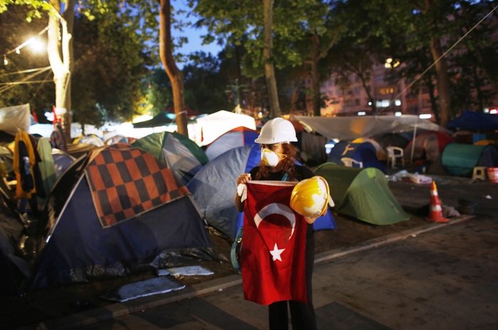 a protester holds a turkish flag as riot police order them to evacuate gezi park in central istanbul june 15 2013 photo reuters