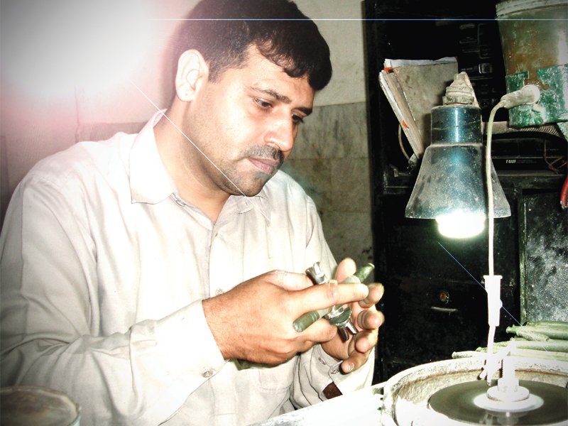 a gem cutter working with a stone on the faceting machine