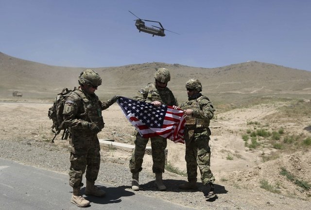 nato soldiers stand with u s flag as a chinook helicopter takes off after a security handover ceremony at a military academy outside kabul june 18 2013 photo reuters