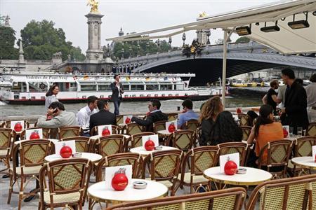 people sit at a terrace cafe near the alexandre iii bridge on the opening day of the new pedestrian walkway area between the orsay museum and alma bridge on the left bank of the river seine in paris photo reuters charles platiau